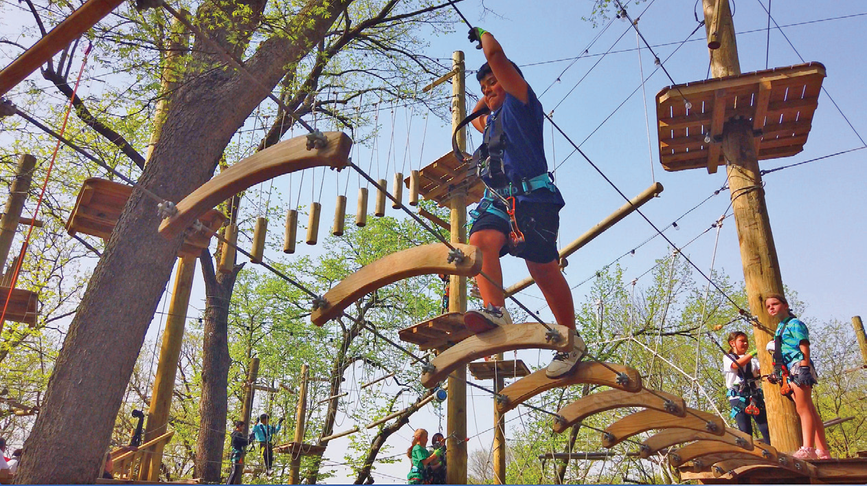 child walking across a wooden platform on ropes course