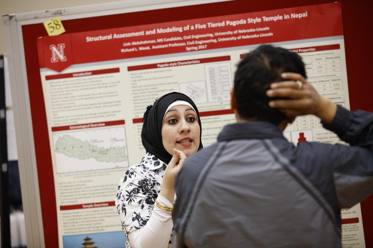 Woman wearing a scarf explains presentation poster