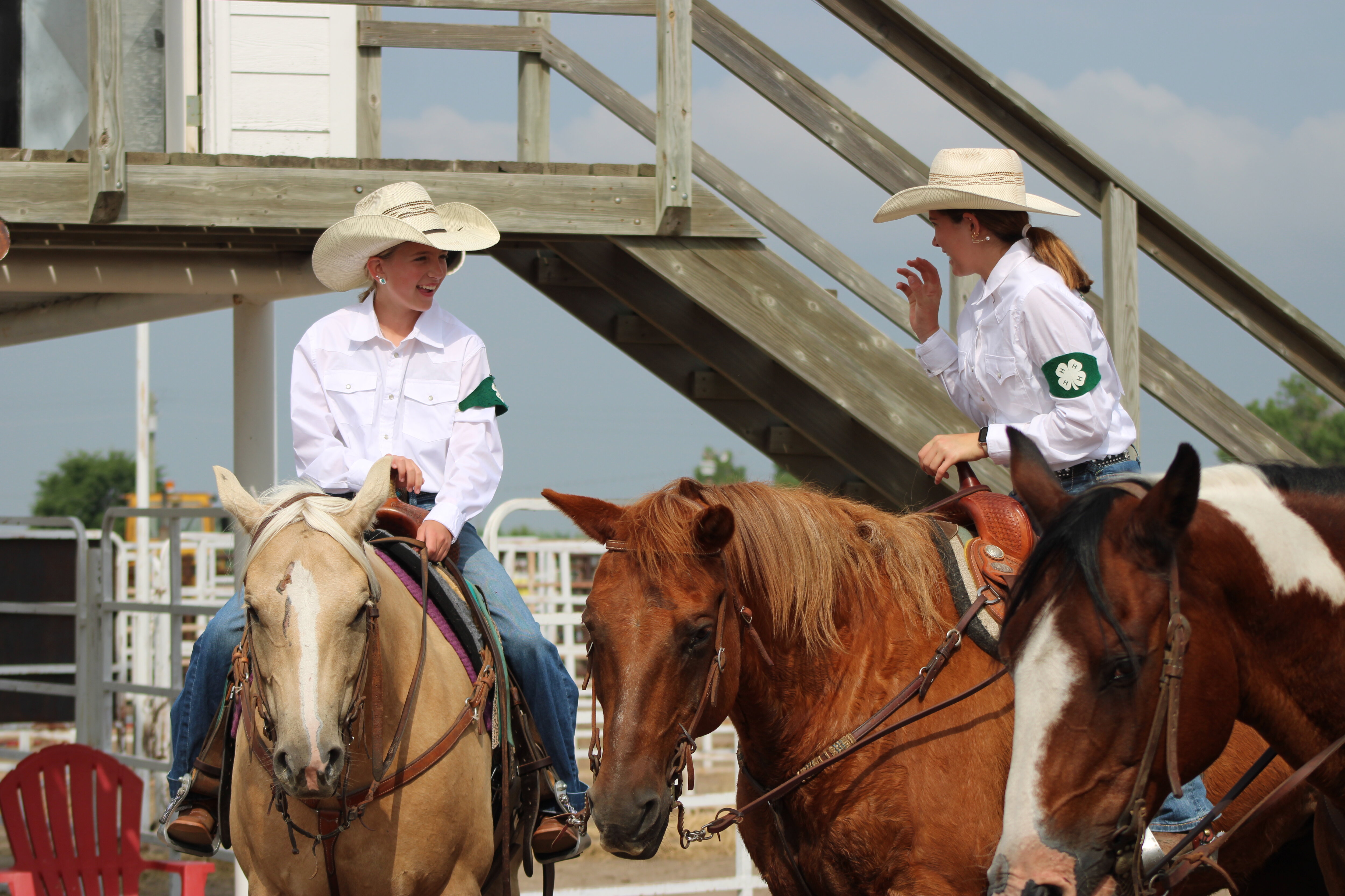 Two girls enjoy laughing while sitting on their horses at the 2024 Cheyenne County horse show