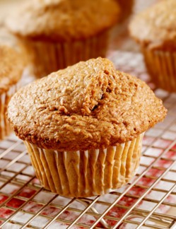 Brown muffin on a cooling rack, with others in blurred background.