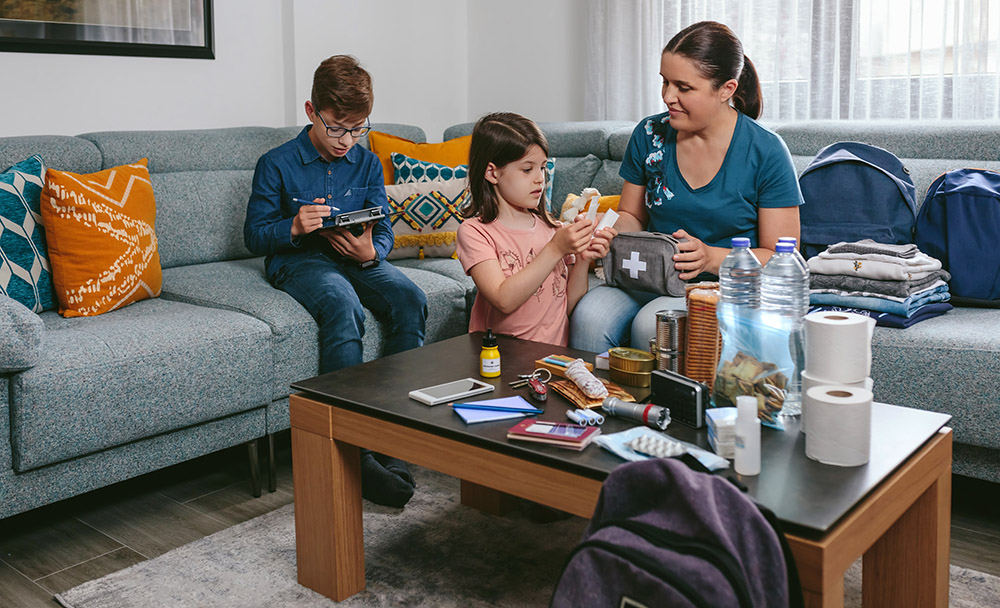 Family organizing emergency supplies on a table in a living room.