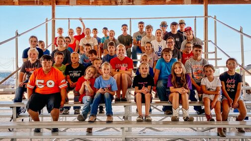 Deuel County 4-H members posing on the bleachers during fair cleanup day.