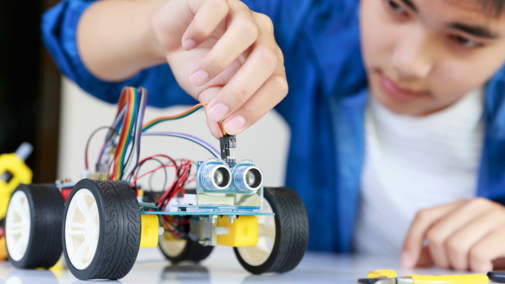 A teenaged boy works on a robotics project