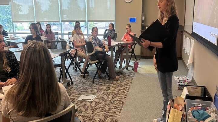 Summer intern teaching a group of students sitting in chairs