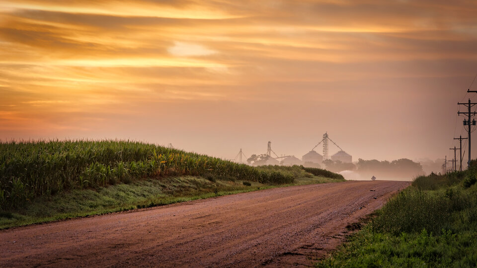 A farm along a country road at sunset.