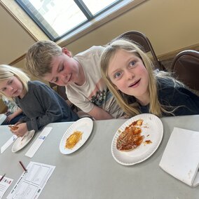 youth making pizza at a table in the library