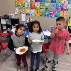 three youth holding their pizza one has thumbs up