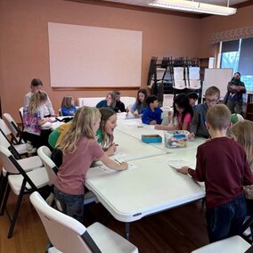 group of youth at a white table eating pizza