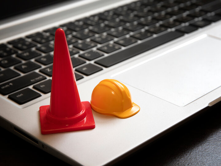tiny hardhat and safety cone on laptop