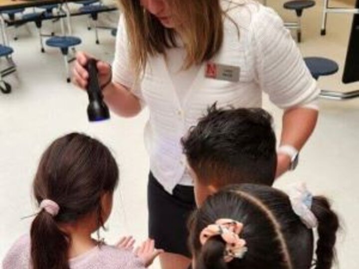 Carla using a special light to show germs on Child's hands