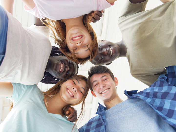 Smiling friends huddled together, looking down at the camera.