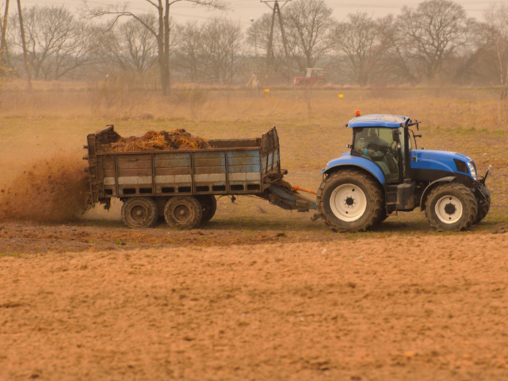 Tractor with manure spreader attached in field