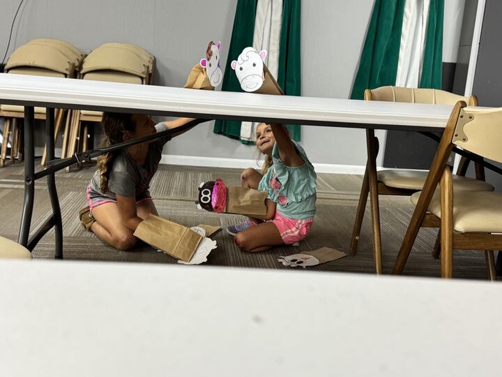 Two youth playing with puppets under a table