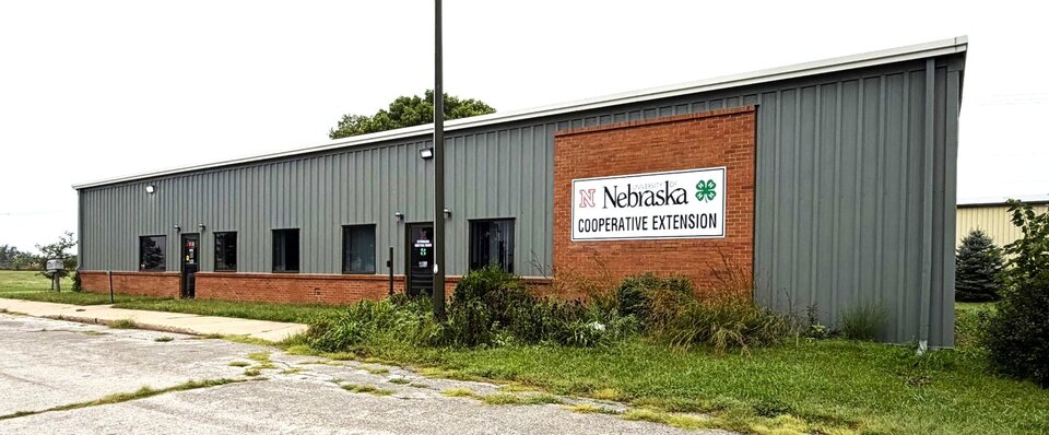 Gray and brick building with "Nebraska Cooperative Extension" sign surrounded by grass.